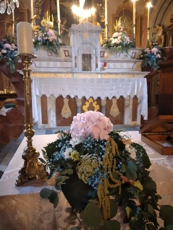Composition de fleurs roses et bleues au pied de l'autel d'une église