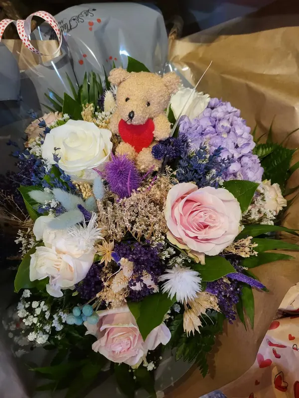 Bouquet rond aux couleurs pastel, avec un ourson