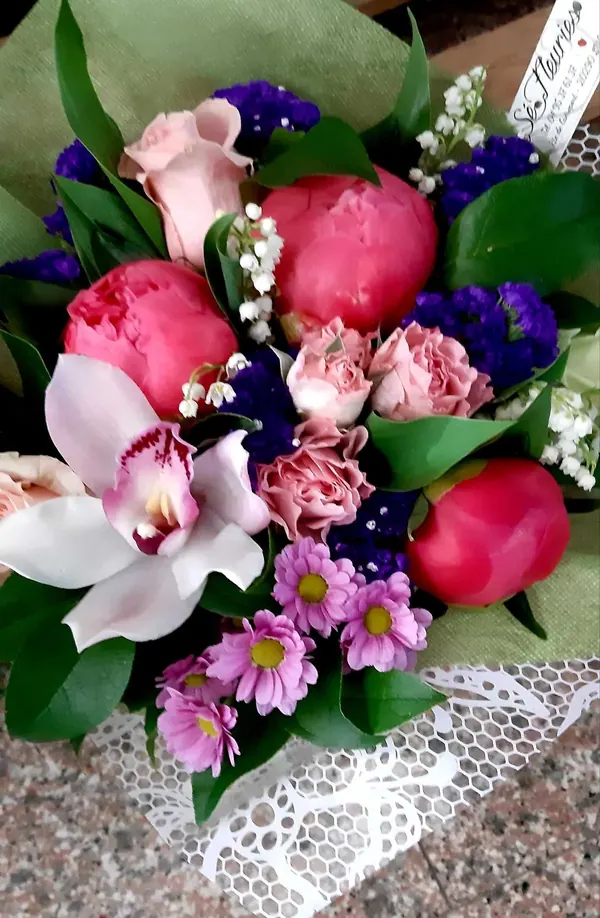 Bouquet de pivoines, d'orchidée et de roses, dans un emballage en dentelle