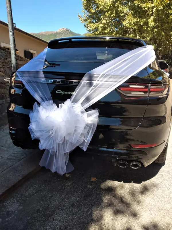 Voiture des mariés décorée d'un grand nœud de tulle blanc