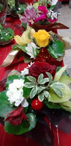 Composition de roses, d'orchidée et de feuillage avec un ruban rouge