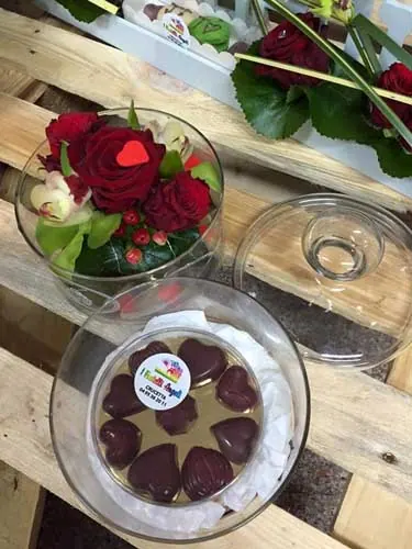 Roses rouges dans une coupe en verre et chocolats en forme de cœur