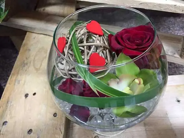 Rose rouge et orchidée dans une coupe en verre décorée de cœurs