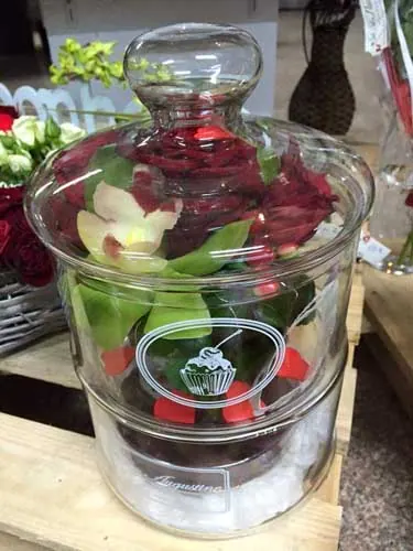 Cloche en verre sur une composition de fleurs rouges et blanches