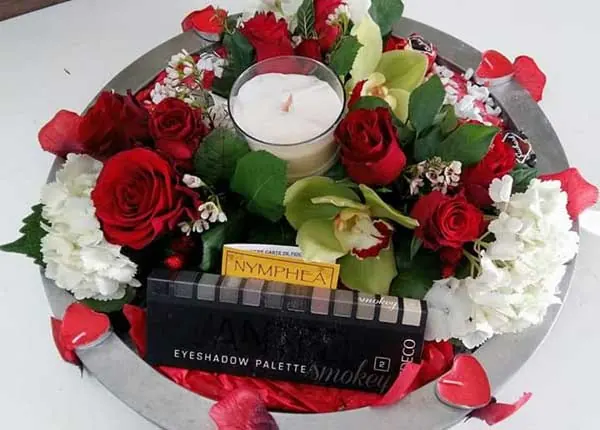 Couronne de roses rouges et d'orchidées autour d'une bougie, avec un coffret cadeau